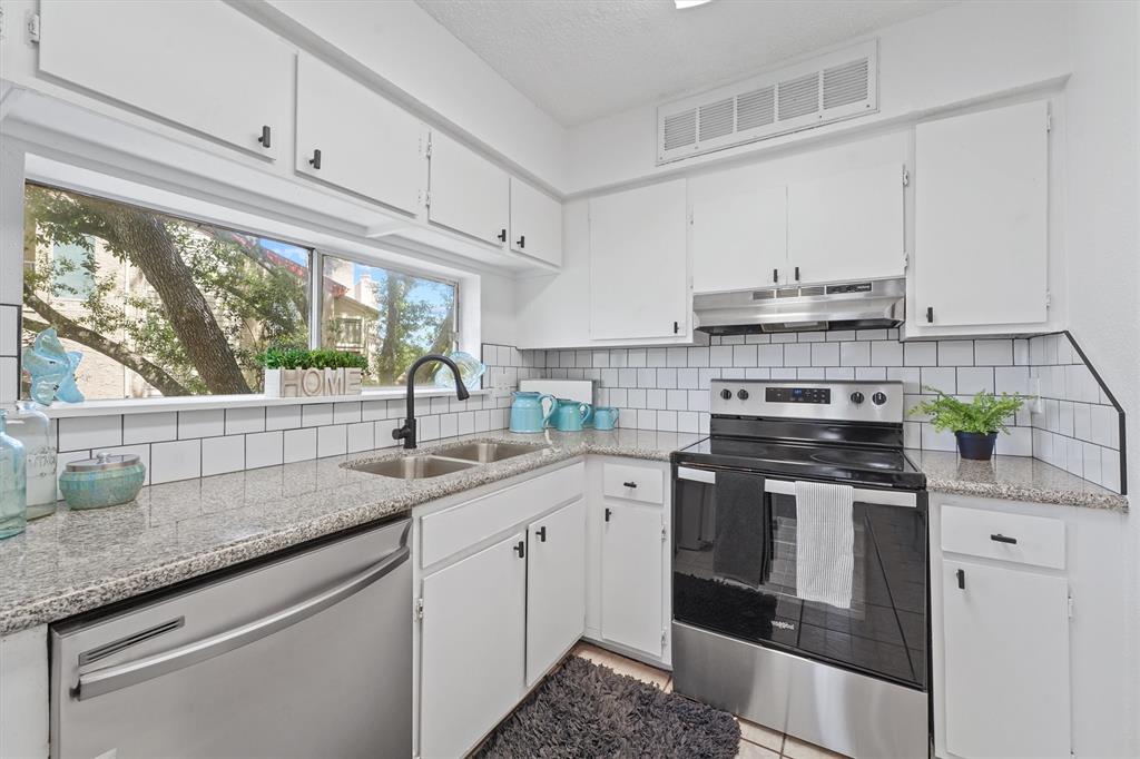 a kitchen with stainless steel appliances granite countertop a sink a stove and a window