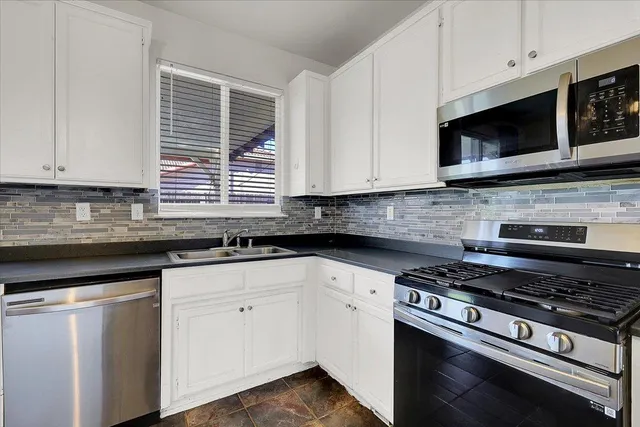 a kitchen with stainless steel appliances a sink and a chandelier