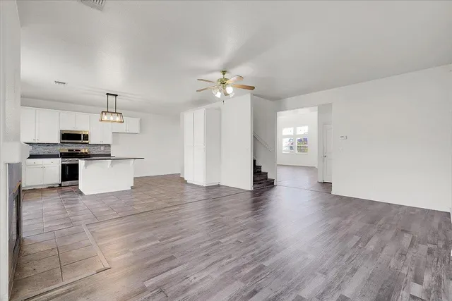 an empty room with wooden floor fireplace and windows