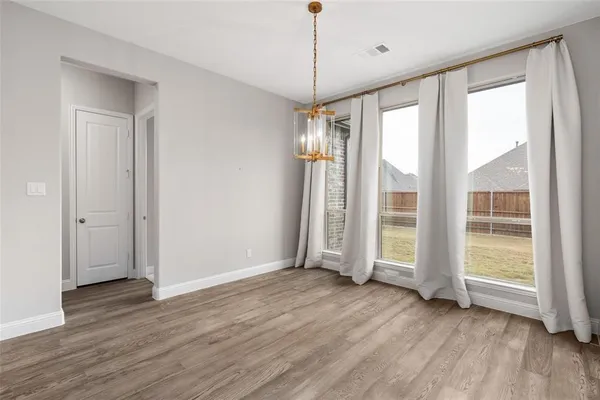 a view of an empty room with wooden floor and a fireplace