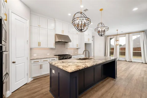 a kitchen with a sink a stove cabinets and wooden floor