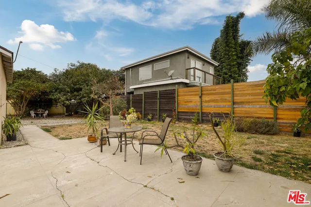 a view of a patio with table and chairs potted plants and a palm tree