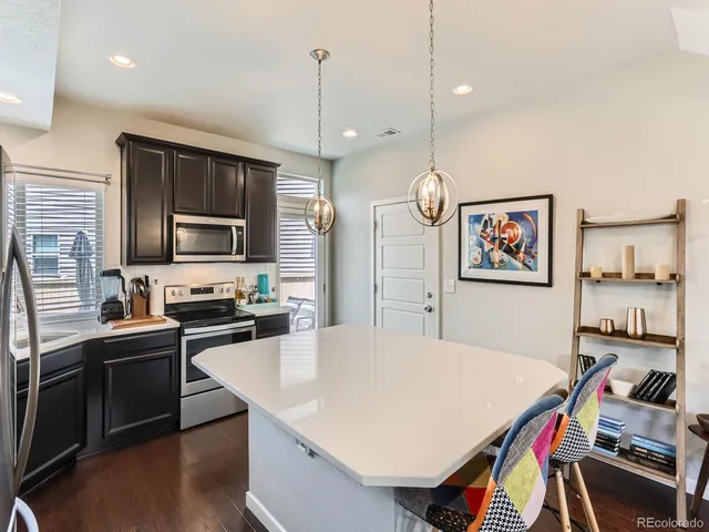 a kitchen with stainless steel appliances a stove sink refrigerator dining table and chairs