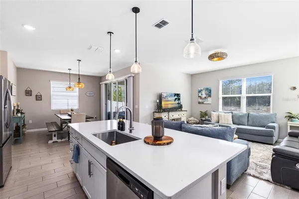 a view of kitchen island with stainless steel appliances sink dining table and chairs