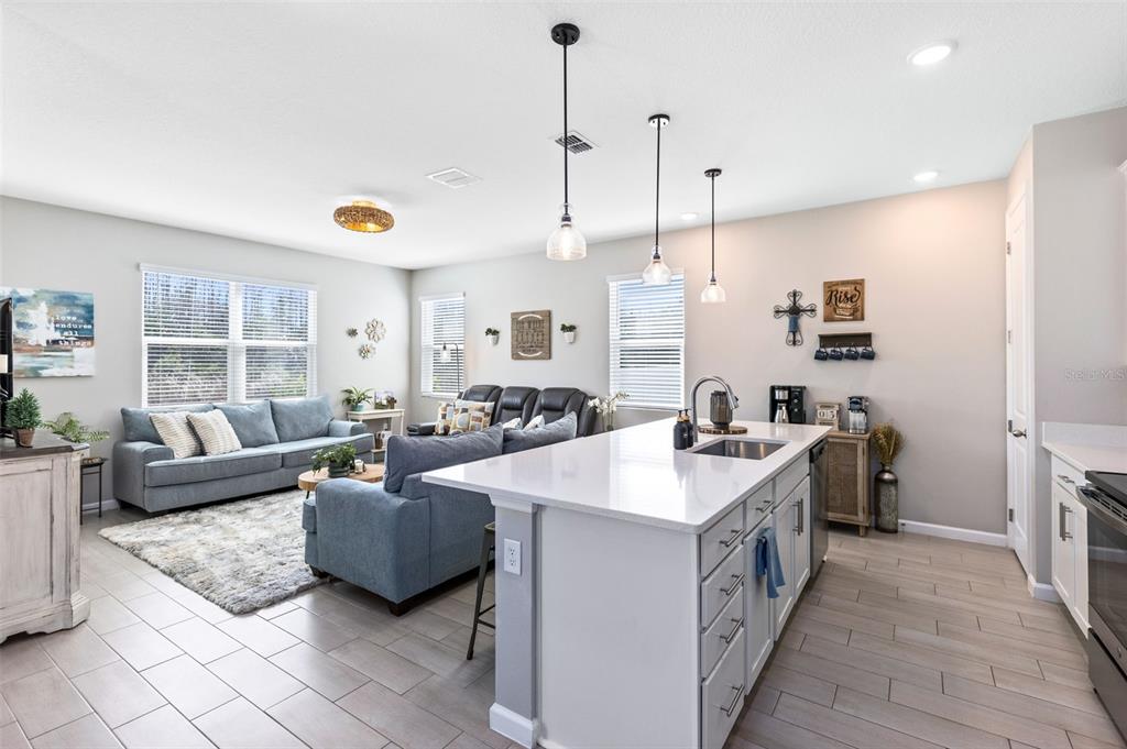 4160 Southern Vista Loop St. Cloud, FL 34772 - Photo 6 of 36 a open kitchen with stainless steel appliances granite countertop a sink a stove and a living room view