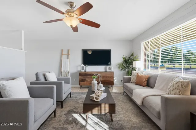 a living room with furniture a flat screen tv and a large window