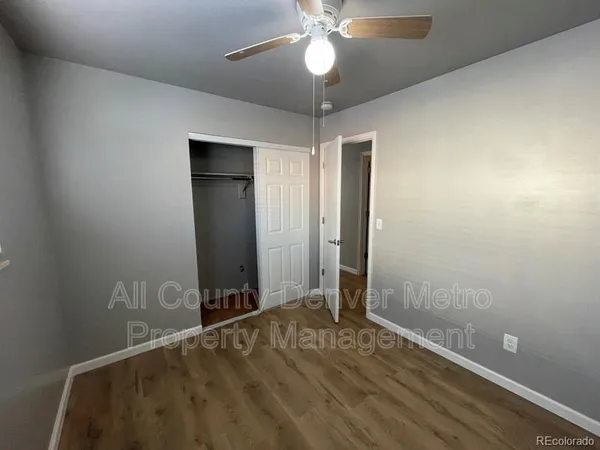 an empty room with closet and a chandelier fan