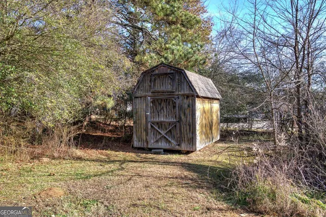 a view of a wooden house with a yard and large trees