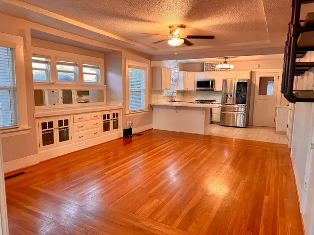 a large kitchen with stainless steel appliances wooden floor and cabinets