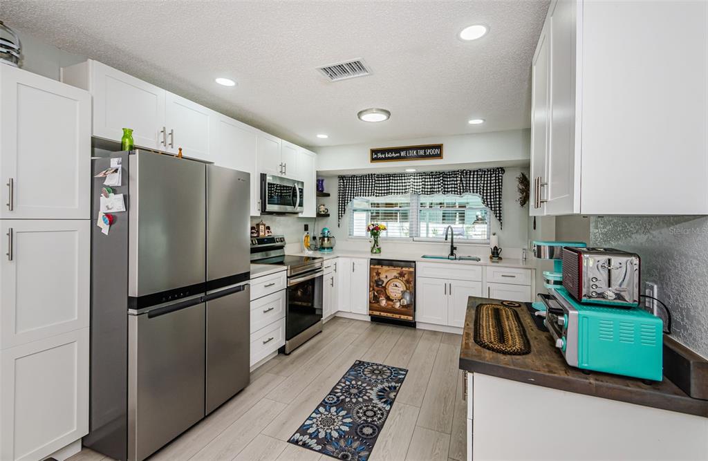 7547 Landmark Drive Spring Hill, FL 34606 - Photo 12 of 34 a kitchen with a refrigerator a sink and a stove top oven