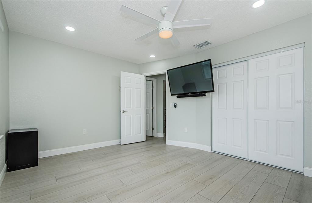 7547 Landmark Drive Spring Hill, FL 34606 - Photo 23 of 34 an empty room with wooden floor a ceiling fan a kitchen space and a window