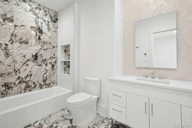a bathroom with a bathtub sink vanity mirror and toilet