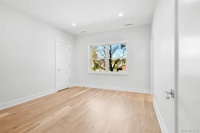 an empty room with wooden floor and window