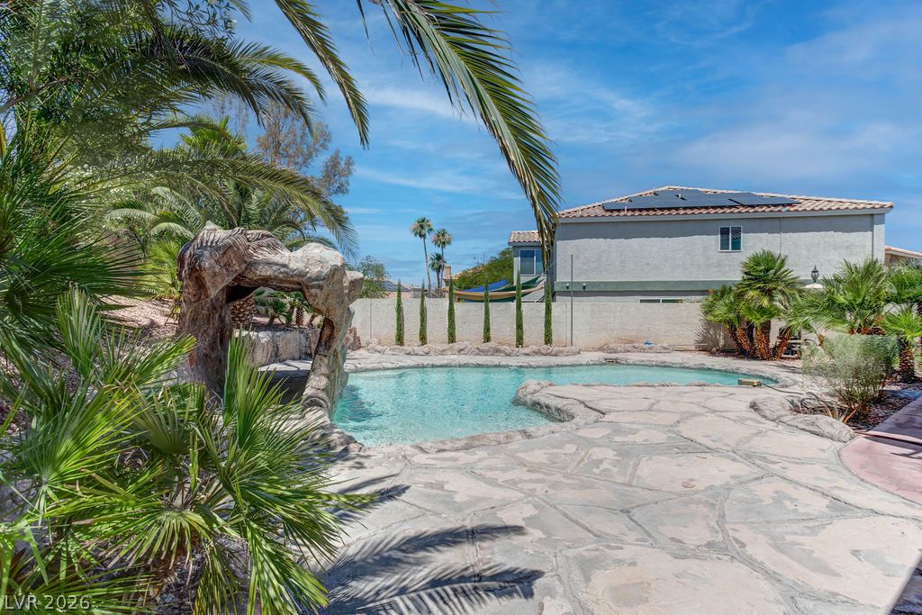 1 Rising Sun Court Henderson, NV 89074 - Photo 41 of 47 A private backyard oasis features a rock-sculpted pool, surrounded by tropical foliage and a generous stone patio.