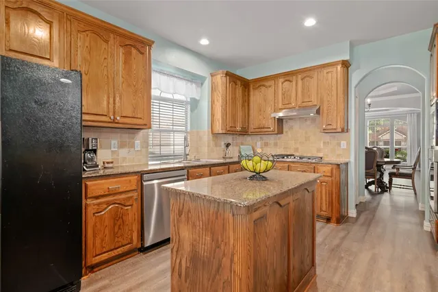 a kitchen with stainless steel appliances granite countertop a sink a stove cabinets counter space and wooden floor