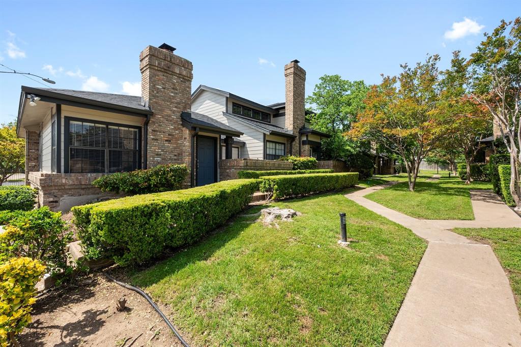 Exterior featuring brick and siding finishes, prominent brick chimney, black trim accents, dark entry door, and a neatly trimmed hedge.
