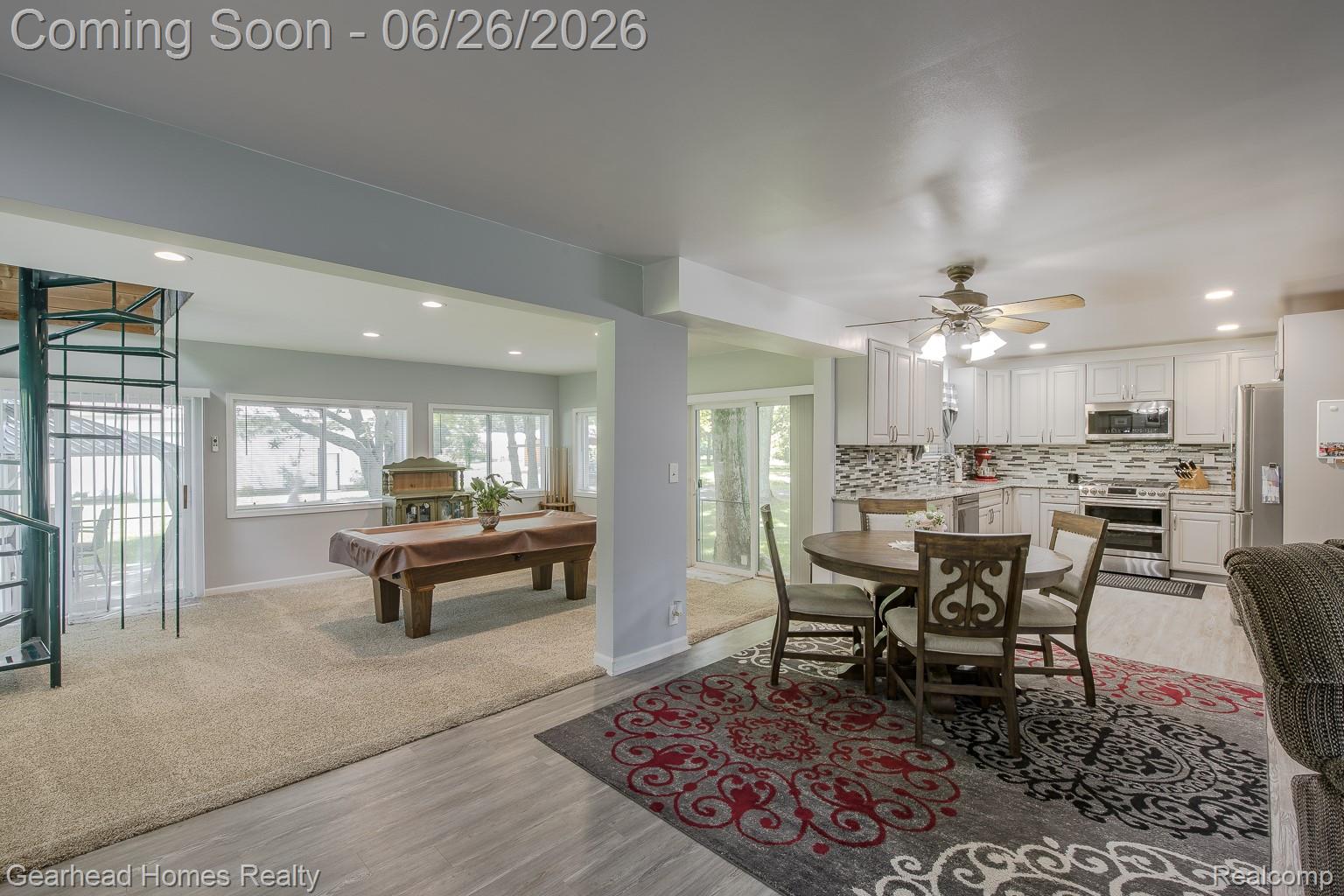 12364 Morrish Road Clio, MI 48420 - Photo 8 of 81 Open-concept living area featuring a spiral staircase, light wood-finish flooring, recessed lighting, and a kitchen with white cabinetry, stainless steel appliances, and a mosaic tile backsplash