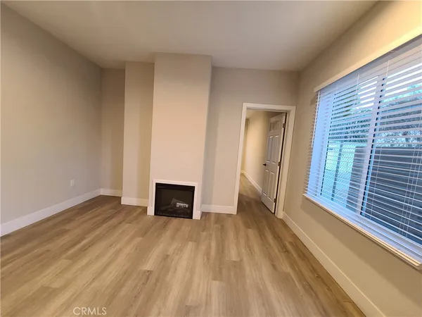 a view of an empty room with window and wooden floor