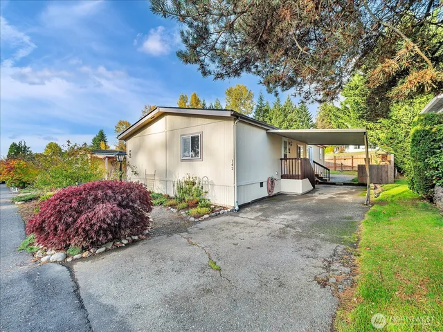 a white house with a large garden plants and large trees