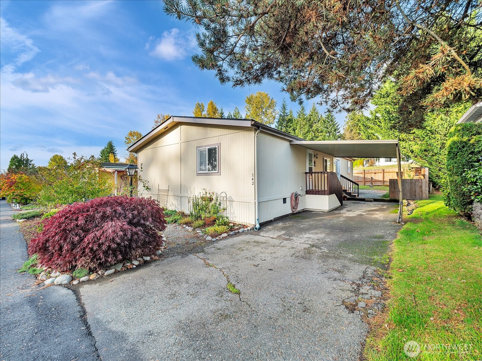 a white house with a large garden plants and large trees