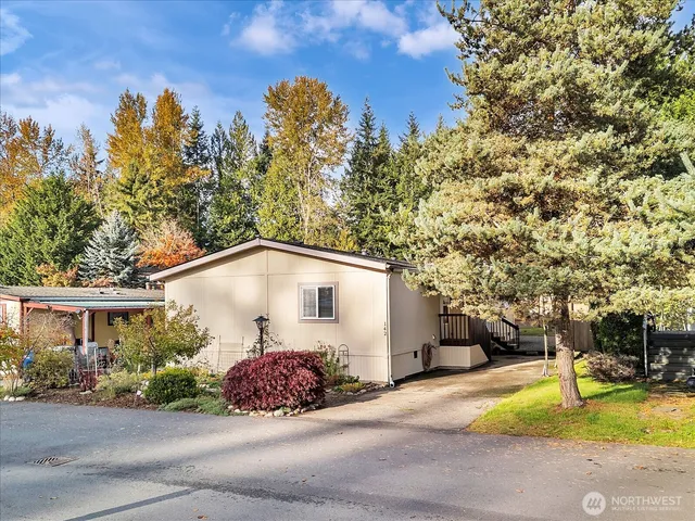 a white house with a large tree and yard in front of it
