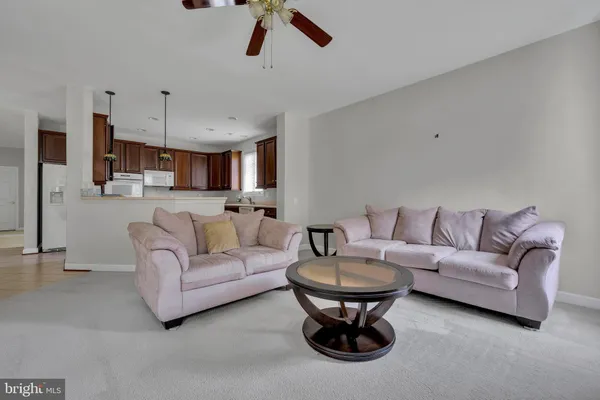 a living room with furniture a kitchen and a chandelier