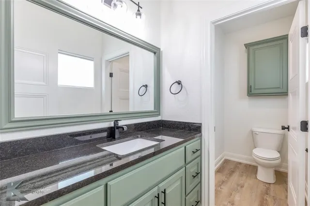 a bathroom with a granite countertop sink a toilet and a mirror