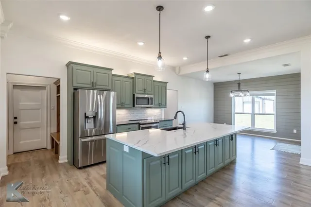 a kitchen with stainless steel appliances granite countertop a sink refrigerator and window