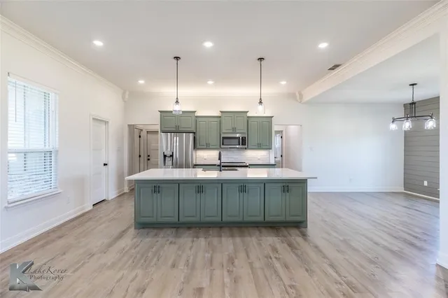 a kitchen with kitchen island stainless steel appliances sink cabinets and wooden floor