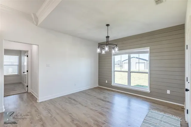 a view of empty room with wooden floor and window