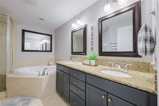 a bathroom with a granite countertop tub double sink and mirror