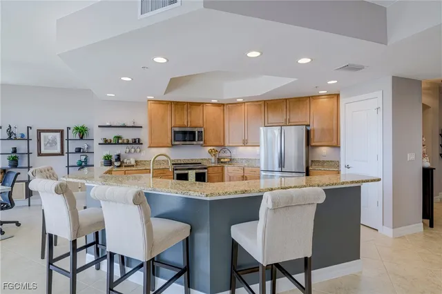 a kitchen with stainless steel appliances a dining table chairs refrigerator and microwave