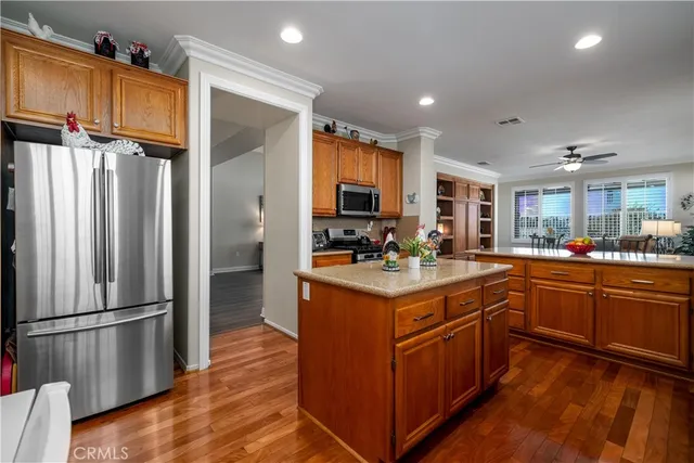 a kitchen with stainless steel appliances granite countertop a refrigerator a sink dishwasher a stove and a dining table with wooden floor