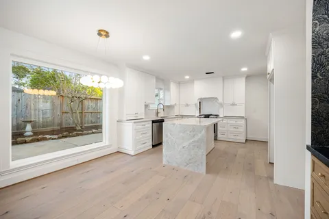 an empty room with wooden floor chandelier and windows