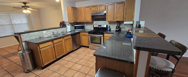 a kitchen with stainless steel appliances granite countertop a sink dishwasher stove refrigerator and cabinets