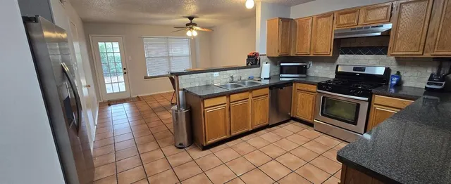 a kitchen with stainless steel appliances granite countertop a stove a sink and a refrigerator