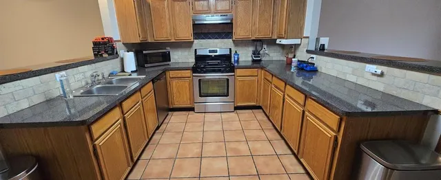 a kitchen with a sink a stove top oven and cabinetry