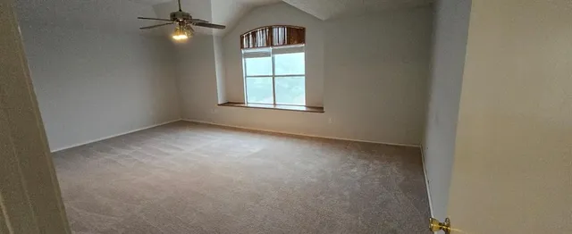 an empty room with windows and fan