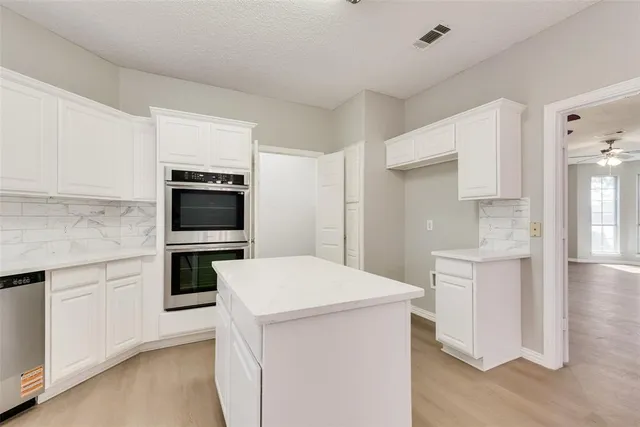 a kitchen with white cabinets appliances a sink and a window