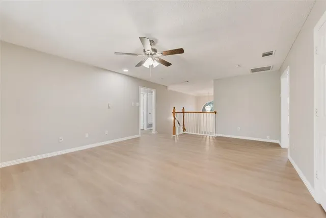 a view of an empty room with chandelier fan and fire place