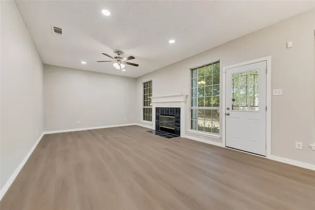 an empty room with fireplace chandelier fan and windows
