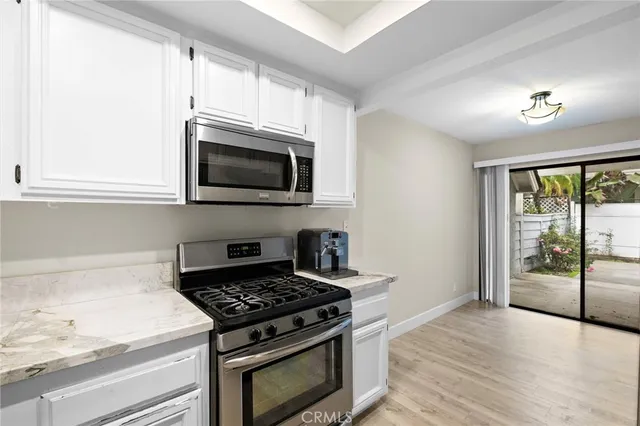 a kitchen with stainless steel appliances a stove a microwave and white cabinets