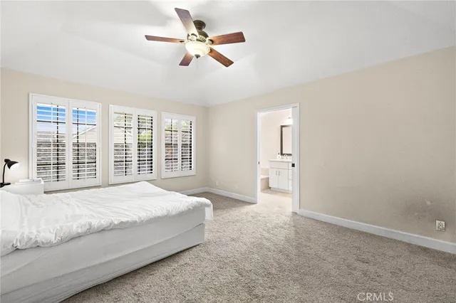 a spacious bedroom with a large bed and a chandelier fan