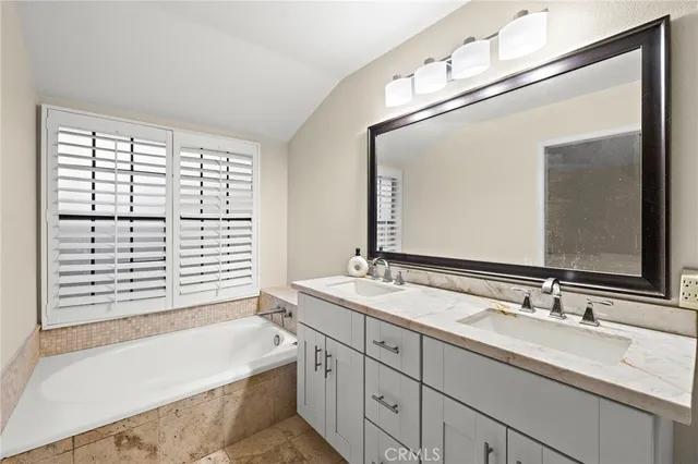 a bathroom with a granite countertop sink mirror and a bathtub