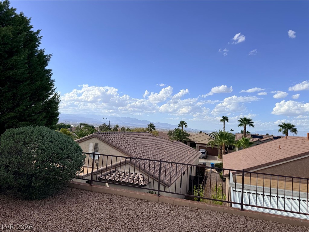 3036 Fort Stanwix Road Henderson, NV 89052 - Photo 2 of 18 Distant mountains frame the neighborhood rooftops and palm trees under a vast blue sky.