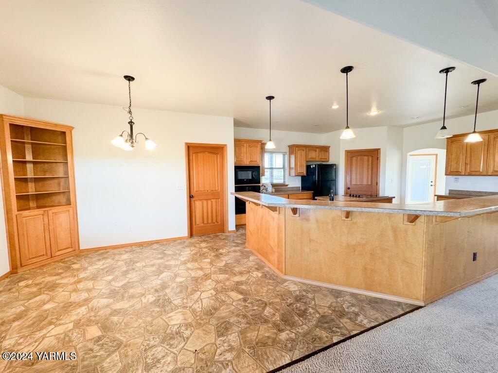 699 Alexander Road Sunnyside, WA 98944 - Photo 12 of 27 a view of a kitchen with kitchen island stainless steel appliances a refrigerator a sink and a wooden floor