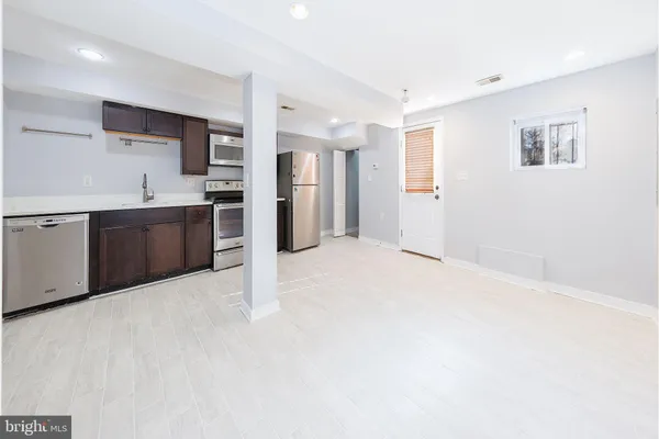 a large white kitchen with kitchen island a sink stainless steel appliances and cabinets