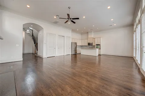 an empty room with wooden floor kitchen appliances and windows