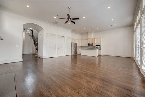 an empty room with wooden floor kitchen appliances and windows