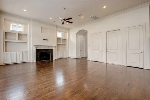 an empty room with wooden floor fireplace and windows